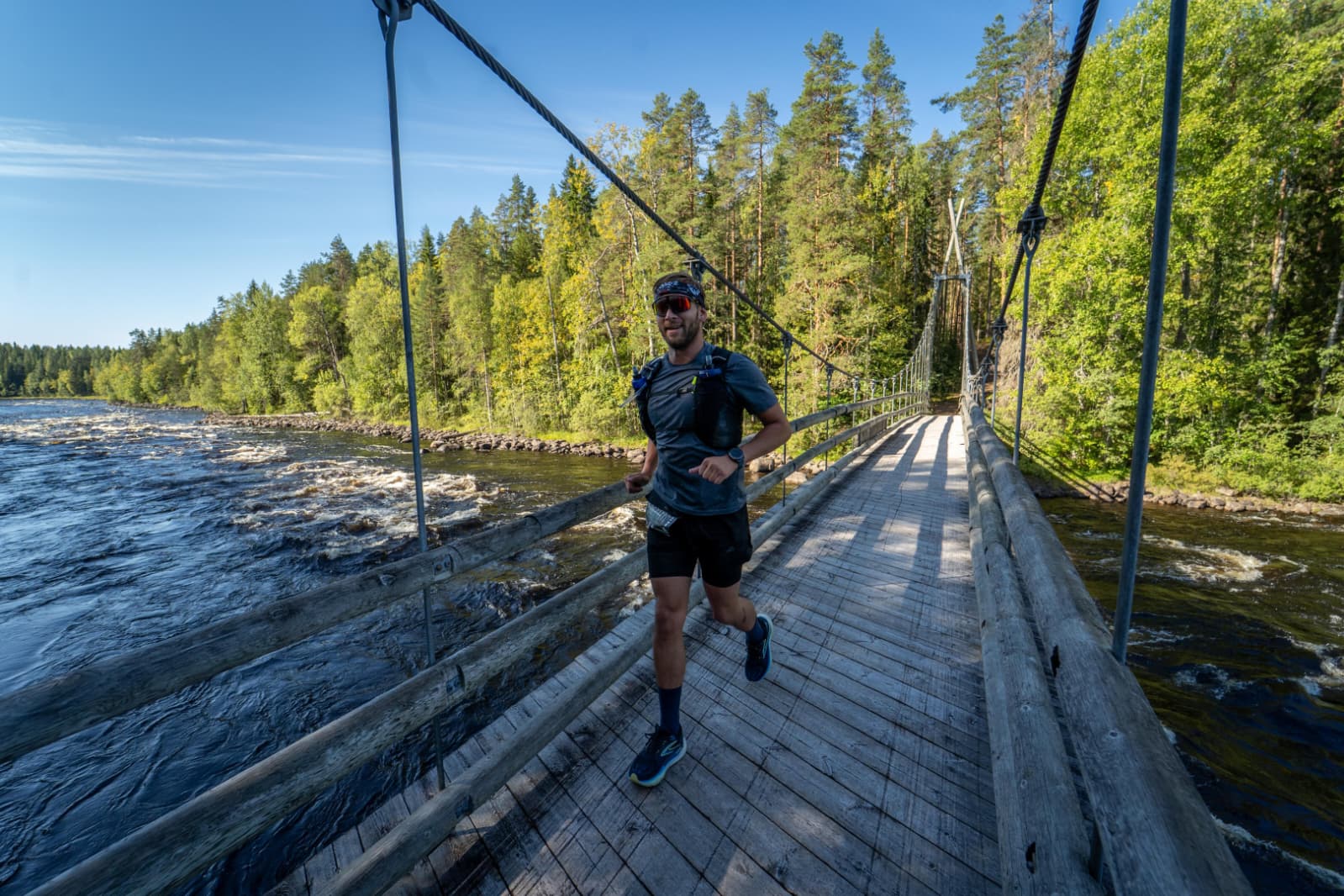 Oscar running across a wooden suspension bridge beside a river during Pogostan